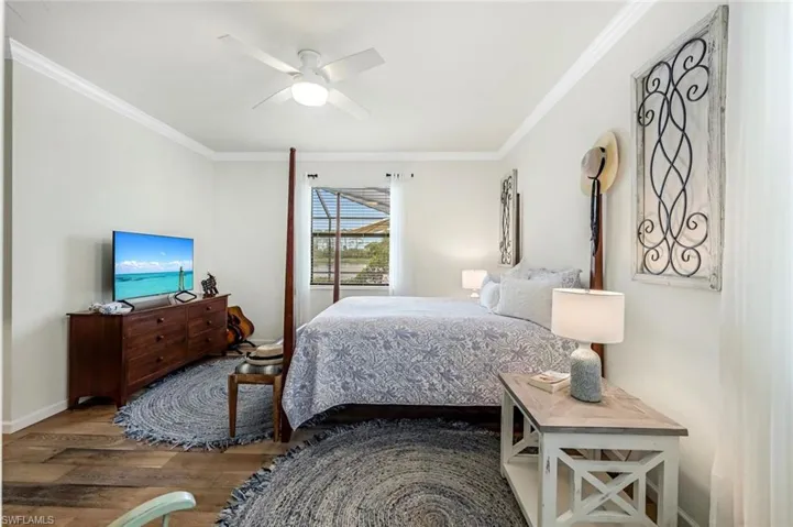 Bedroom with ceiling fan, ornamental molding, and wood-type flooring