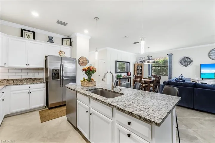 Kitchen with white cabinetry, an island with sink, stainless steel appliances, decorative light fixtures, and sink