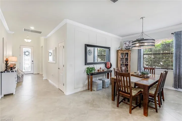 Dining room with a healthy amount of sunlight, ornamental molding, and an inviting chandelier