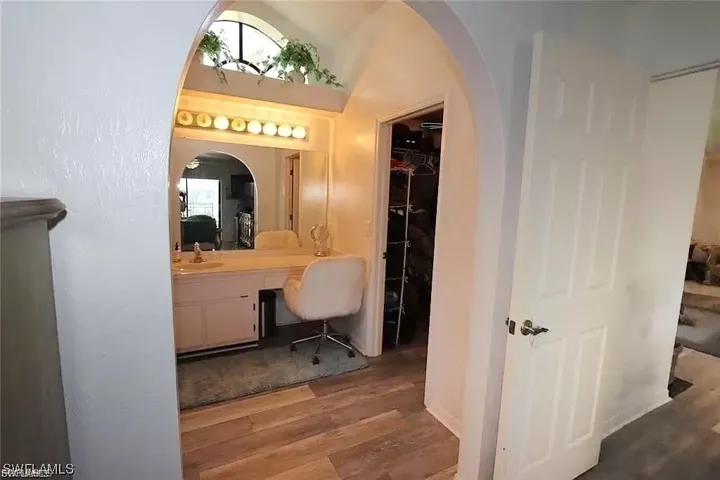 Bathroom with vanity, wood finished floors, and a walk in closet