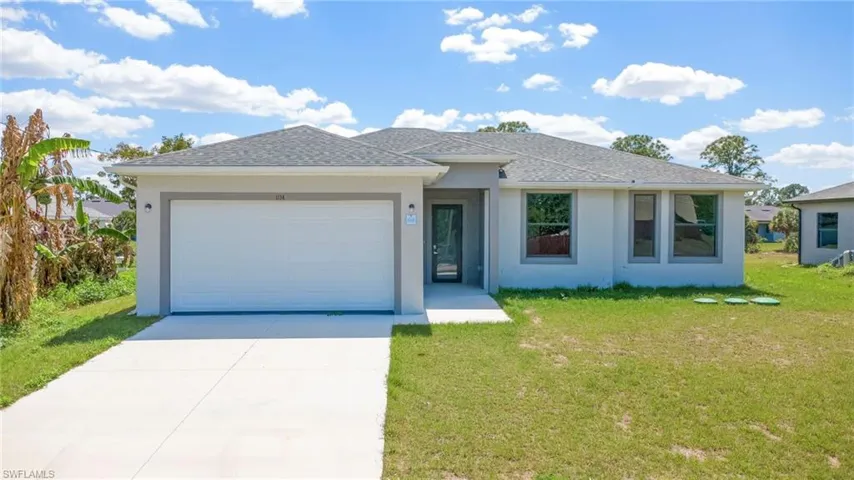 View of front of home with a garage, a front yard, driveway, stucco siding, and roof with shingles