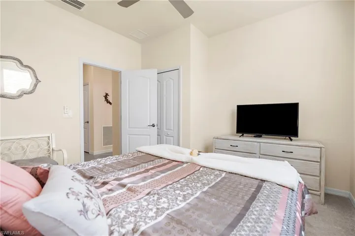 Carpeted bedroom with ceiling fan and a closet