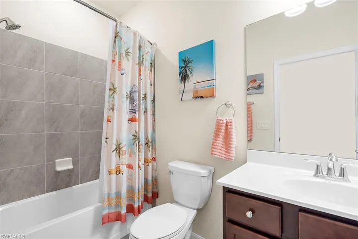 Full bathroom with vanity, shower / bath combination with curtain, and toilet