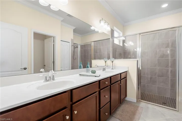 Bathroom with tile patterned flooring, vanity, ornamental molding, and walk in shower