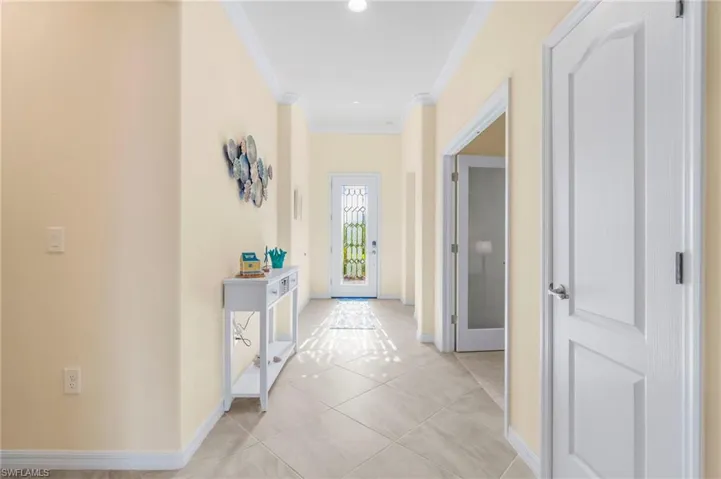 Corridor featuring ornamental molding and light tile patterned flooring