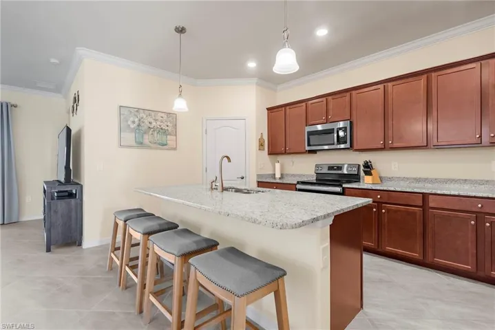 Kitchen with a center island with sink, ornamental molding, and stainless steel appliances