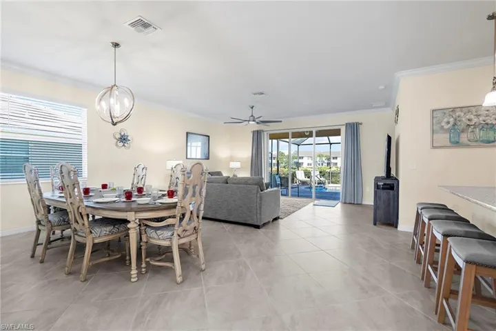 Tiled dining space featuring ceiling fan with notable chandelier and ornamental molding