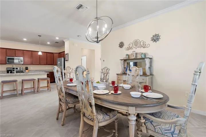 Tiled dining space with crown molding and a chandelier