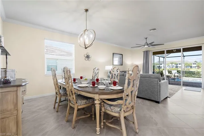Tiled dining space featuring ceiling fan with notable chandelier and crown molding