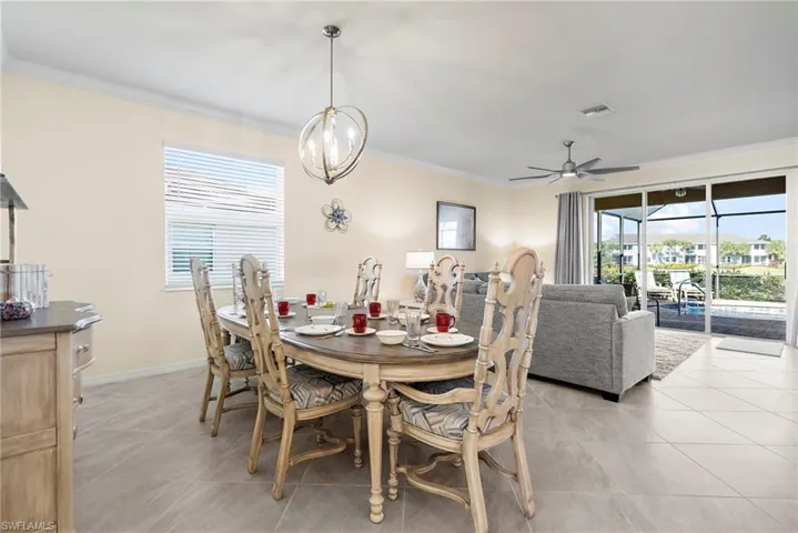 Tiled dining space with plenty of natural light, crown molding, and ceiling fan with notable chandelier