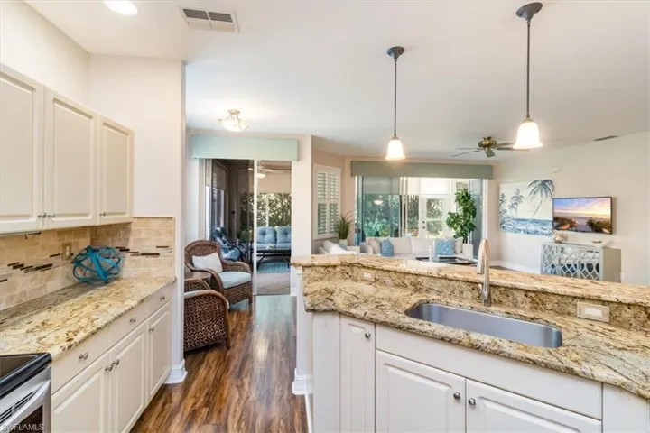 Kitchen featuring decorative light fixtures, backsplash, sink, and light neutral cabinetry