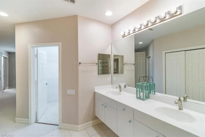Master bathroom with private loo, tile floors, vanity with extensive cabinet space, and dual sinks