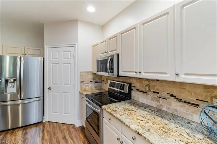Kitchen featuring stainless steel appliances, light stone counters, and backsplash to bring natural tones and beachy feel to the room.