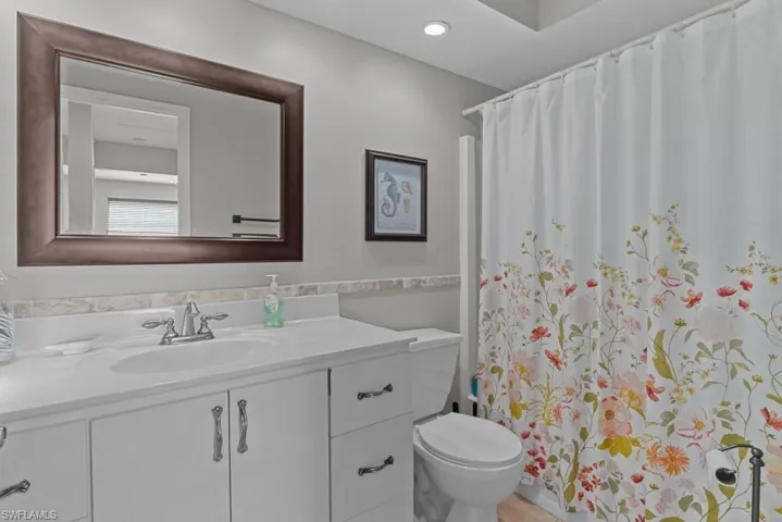 Bathroom with vanity, curtained shower, and toilet