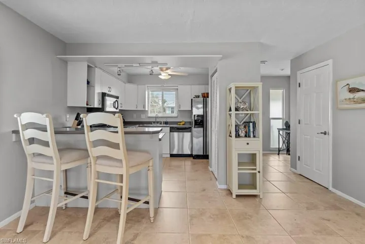Kitchen with appliances with stainless steel finishes, white cabinetry, sink, ceiling fan, and kitchen peninsula