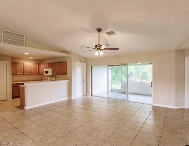 Spacious open-concept living area featuring tile flooring, vaulted ceilings, and a ceiling fan