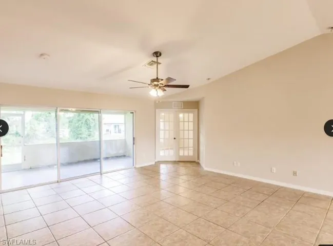 Spacious room with tile flooring, featuring a ceiling fan, sliding glass doors to a balcony, and double French doors with multiple panes