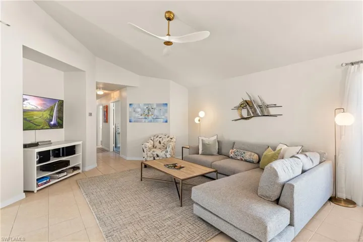 Tiled living room with ceiling fan and vaulted ceiling