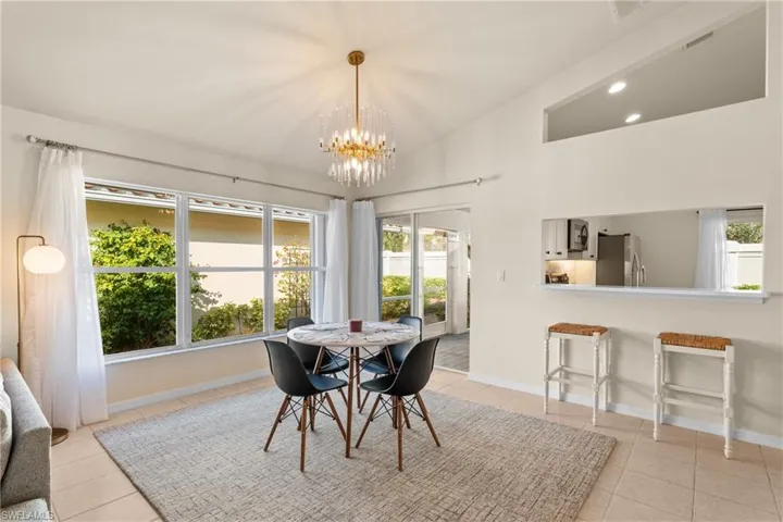 Tiled dining space featuring a notable chandelier and lofted ceiling