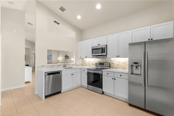 Kitchen with white cabinets, stainless steel appliances, kitchen peninsula, and sink