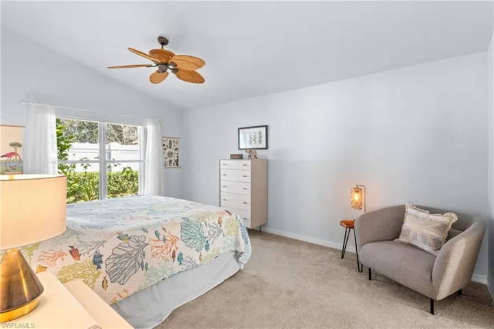 Bedroom featuring vaulted ceiling, ceiling fan, and light carpet