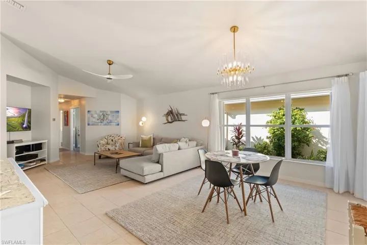Dining space featuring vaulted ceiling, ceiling fan with notable chandelier, and light tile patterned floors
