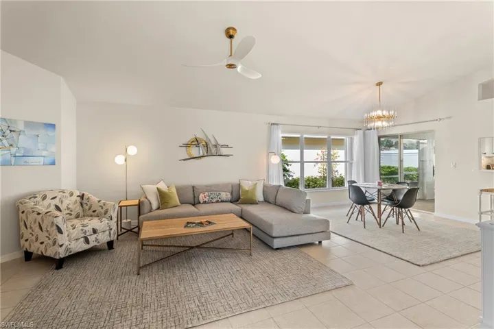 Living room featuring ceiling fan with notable chandelier and light tile patterned floors