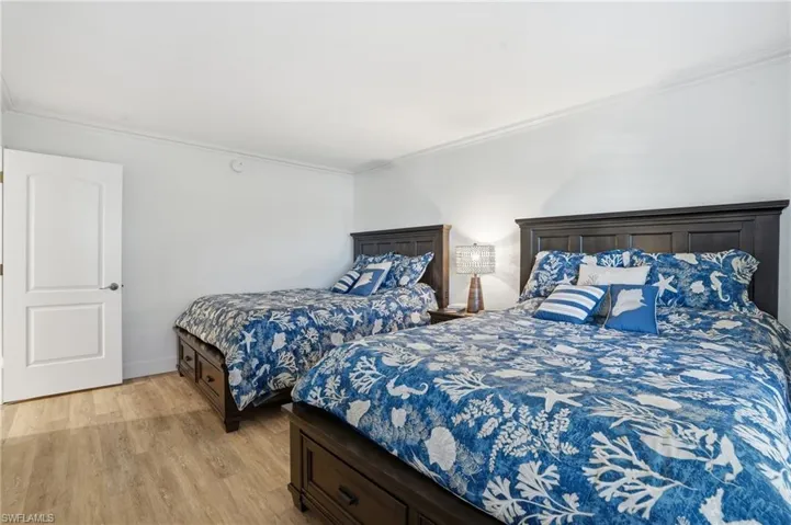 Bedroom with crown molding and light wood finished floors - Virtually Edited Image