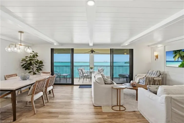 Open-concept living space with expansive water views from a private balcony - Virtually Edited Image