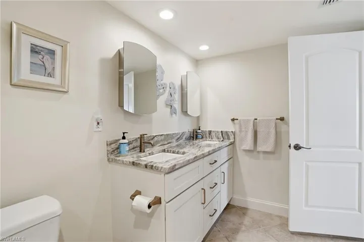 Full bath featuring double vanity, light tile patterned floors, and recessed lighting - Virtually Edited Image