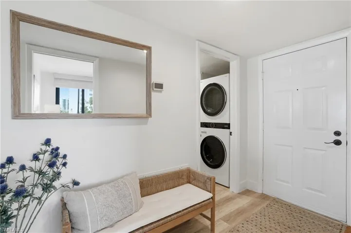 Laundry area with light wood-type flooring and stacked washing machine and dryer - Virtually Edited Image