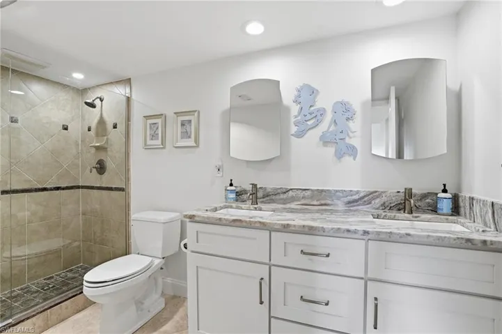 Full bath featuring double vanity, a shower stall, and recessed lighting - Virtually Edited Image