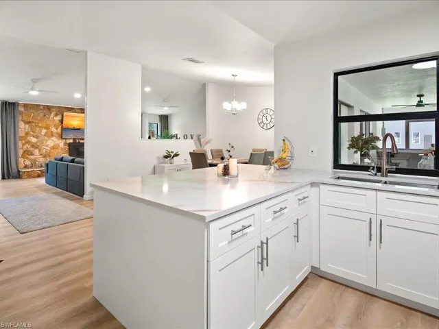 Kitchen with a ceiling fan, open floor plan, light wood-type flooring, and white cabinetry