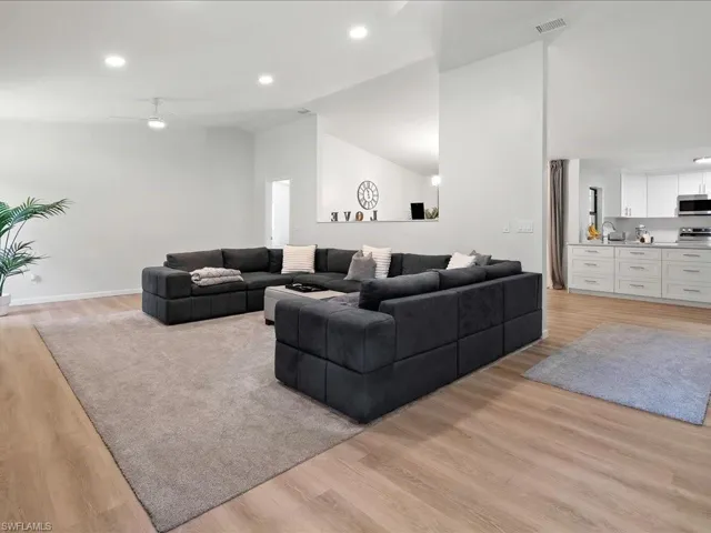 Living room featuring recessed lighting, ceiling fan, light wood-type flooring, and high vaulted ceiling