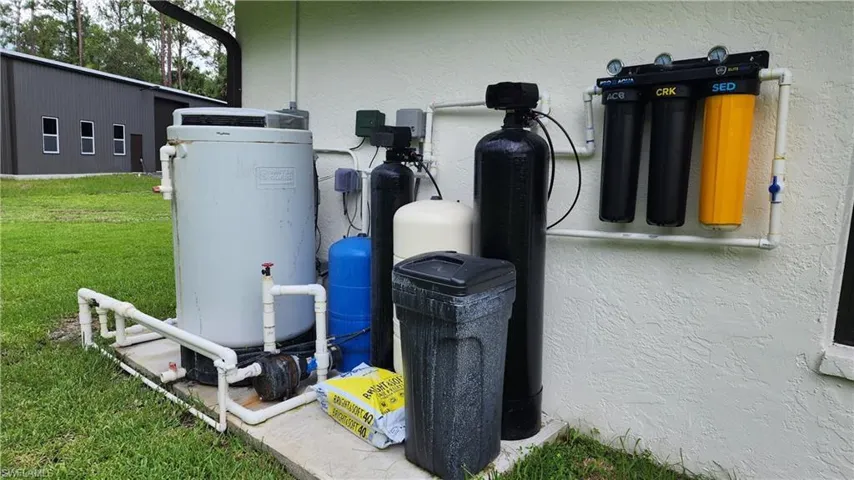 Exterior view of a water pressure tank, a water softener system, and stucco siding