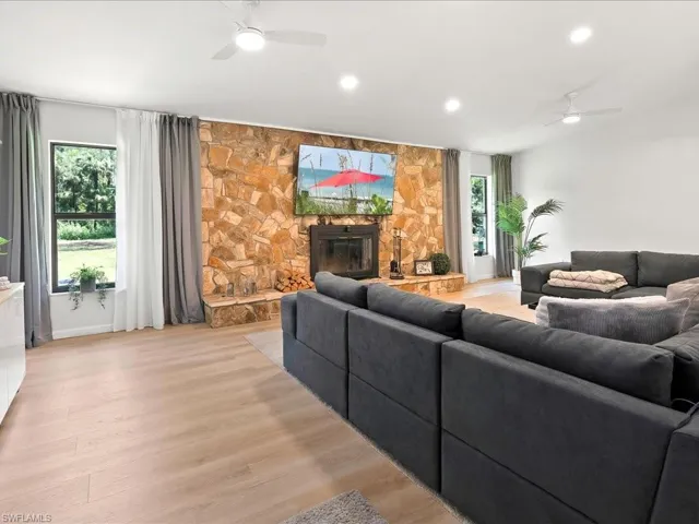 Living room featuring a ceiling fan, light wood-type flooring, a fireplace, and recessed lighting