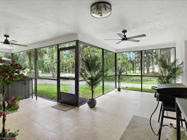 Unfurnished sunroom with a ceiling fan, tile patterned flooring, and a wall of windows