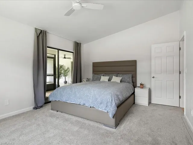 Carpeted bedroom featuring vaulted ceiling and ceiling fan