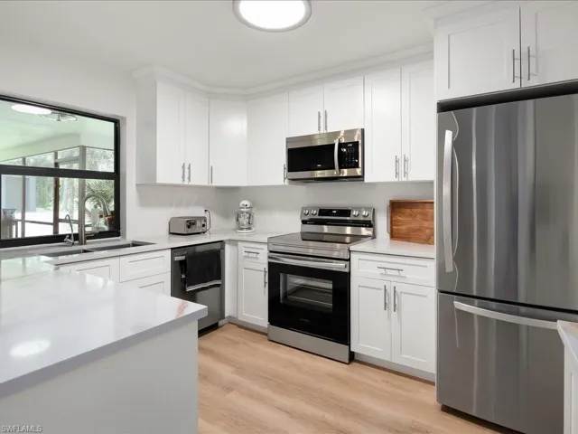 Kitchen with appliances with stainless steel finishes, light countertops, white cabinetry, and light wood-style floors
