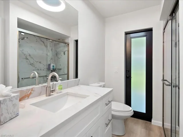Full bathroom with a marble finish shower, vanity, and wood finished floors