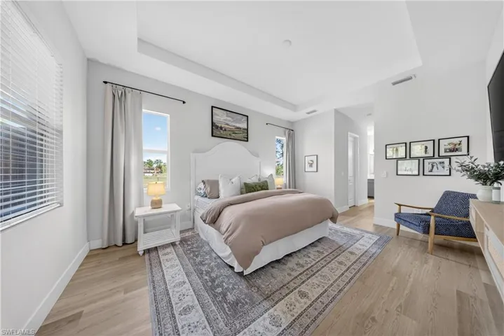 Bedroom with a raised ceiling and light wood finished floors