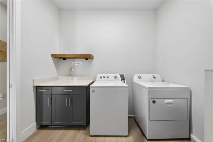 Laundry room featuring light wood-type flooring, washing machine and clothes dryer, and cabinet space
