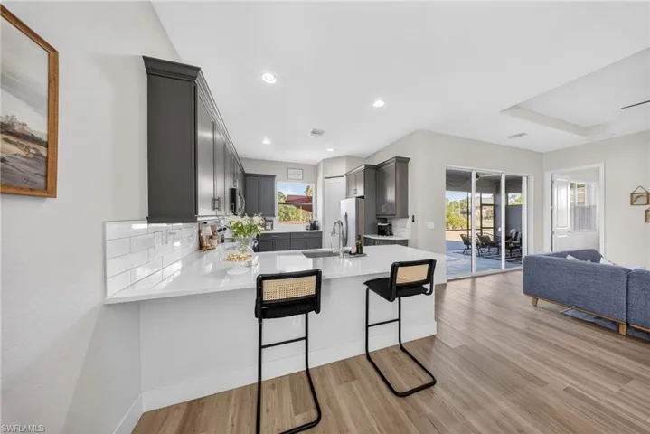 Kitchen featuring a peninsula, gray cabinets, light wood-type flooring, a kitchen bar, and recessed lighting