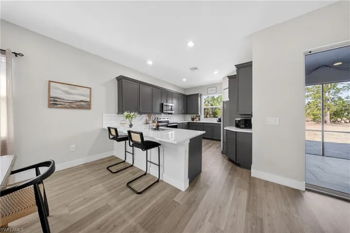 Kitchen featuring a kitchen breakfast bar, a peninsula, light wood finished floors, stainless steel appliances, and tasteful backsplash