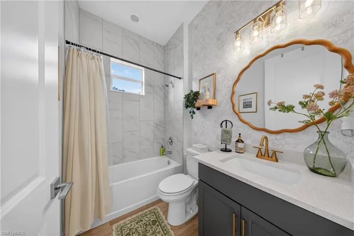 Bathroom featuring vanity, shower / bath combo with shower curtain, and light wood finished floors