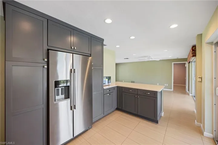 Kitchen featuring appliances with stainless steel finishes, recessed lighting, a peninsula, light tile patterned floors, and light stone counters