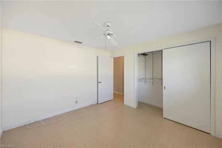 Unfurnished bedroom with ceiling fan and a closet
