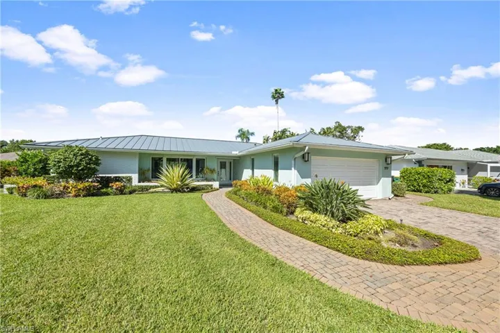 Single story home with a front yard, stucco siding, a garage, and decorative driveway