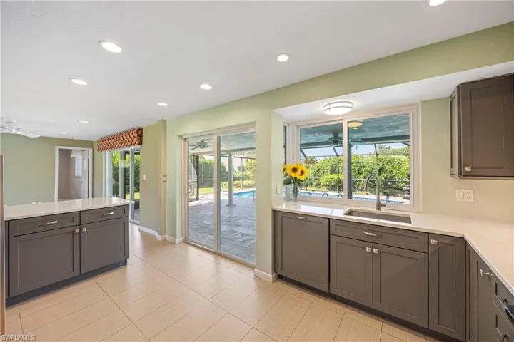 Kitchen featuring recessed lighting, light stone countertops, gray cabinets, paneled dishwasher, and a peninsula