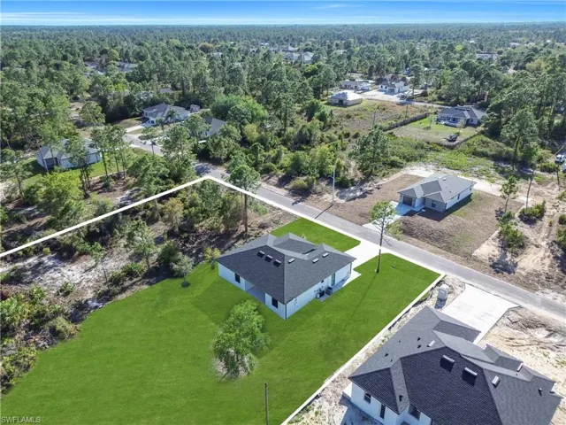 Aerial view of residential area featuring property boundaries highlighted and a heavily wooded area